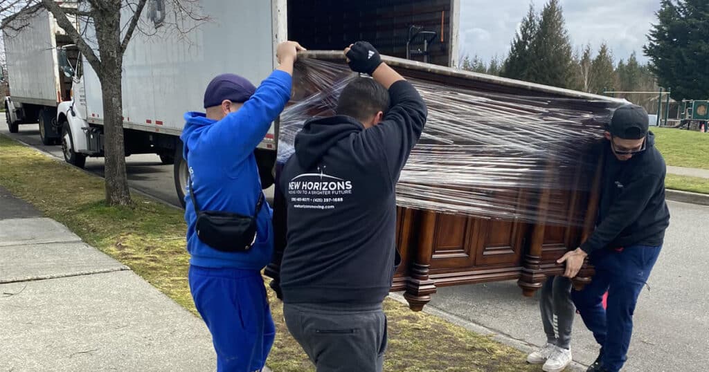 Tacoma movers lifting a large dresser into truck