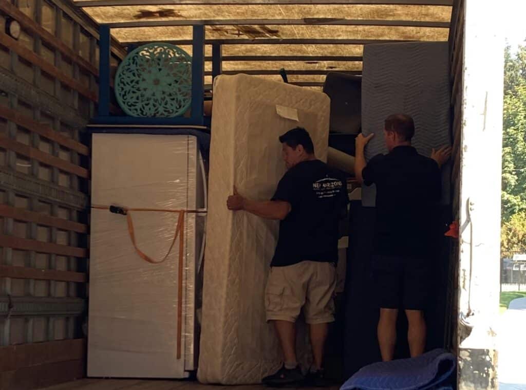 movers in the back of a moving truck arranging furniture